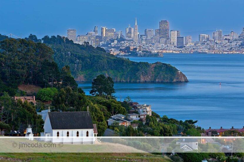 This is a photo of old St. Hilary's Church in the town of Tiburon at dusk with Angel Island, Alcatraz and the San Francisco skyline in the background..